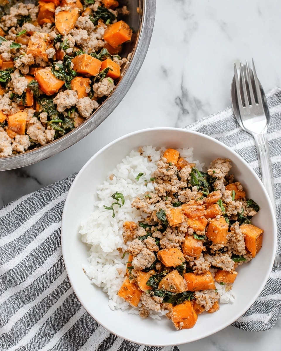 A white bowl filled with a base layer of fluffy white rice, topped with a mix of light brown cooked ground meat and bright orange cubed sweet potatoes, with scattered pieces of green leafy herbs mixed in. Next to the bowl is a large silver mixing bowl containing more of the meat, sweet potato, and herb mixture, placed on a white marble surface with a grey and white striped cloth underneath. A silver fork is visible near the top right corner. Photo taken with an iphone --ar 4:5 --v 7