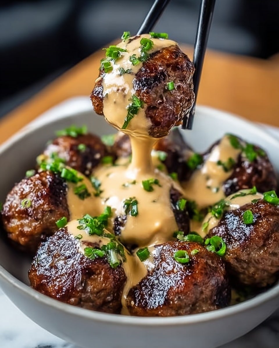 The image shows a white bowl filled with eight glossy, dark brown meatballs that look juicy and grilled. Each meatball is covered with a thick, creamy beige sauce that drips down the sides, giving a rich texture. Small pieces of fresh green chopped herbs are sprinkled on top of the meatballs, adding a pop of color and freshness. A pair of black chopsticks held by a woman's hand is lifting one meatball from the bowl, showing the sauce dripping off it. The background is a soft blur with a white marbled texture surface beneath the bowl. Photo taken with an iphone --ar 4:5 --v 7