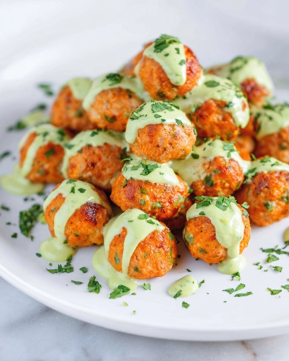 A close-up view of a fork holding a single orange-brown fried ball coated with green herbs, drizzled with a light green sauce, with several similar balls blurred in the background on a white plate that rests on a white marbled surface, showing a crispy texture and fresh garnishing, photo taken with an iphone --ar 4:5 --v 7