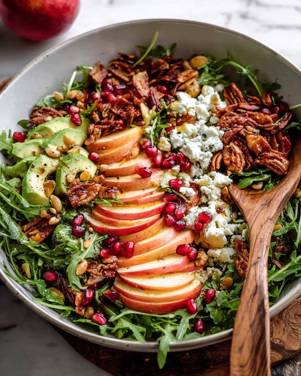 A large white bowl filled with a colorful salad that has several layers: the base layer is fresh green arugula leaves, on top are thin slices of red apple with crisp texture, scattered with bright red pomegranate seeds. There are creamy white crumbles of cheese spread around, along with chunks of avocado. Crunchy toasted seeds and nuts add a rough texture, and some crispy thin brown slices, possibly bacon, are layered on top. A wooden spoon rests inside the bowl on a white marbled surface nearby. photo taken with an iphone --ar 4:5 --v 7