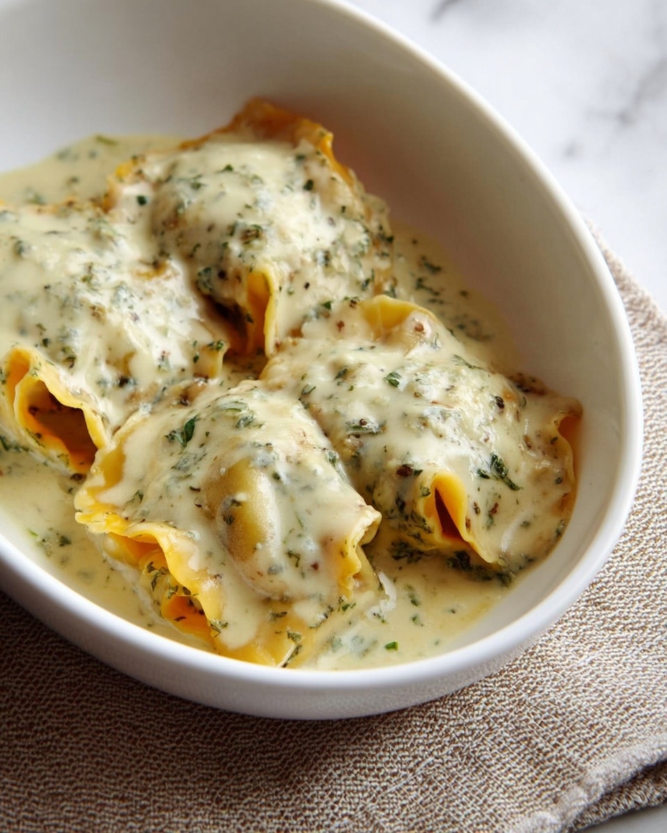 Two rolled pasta pieces lie side by side on a white plate with a thin gold edge, resting on a white marbled surface. Each roll shows visible layers of wavy yellow pasta, filled with small chunks of browned meat and soft orange cheese. The rolls are covered in a creamy white sauce speckled with green herbs, some sauce pooling slightly on the plate. In the background, there is a blurred white bowl filled with fresh green leafy salad. photo taken with an iphone --ar 4:5 --v 7