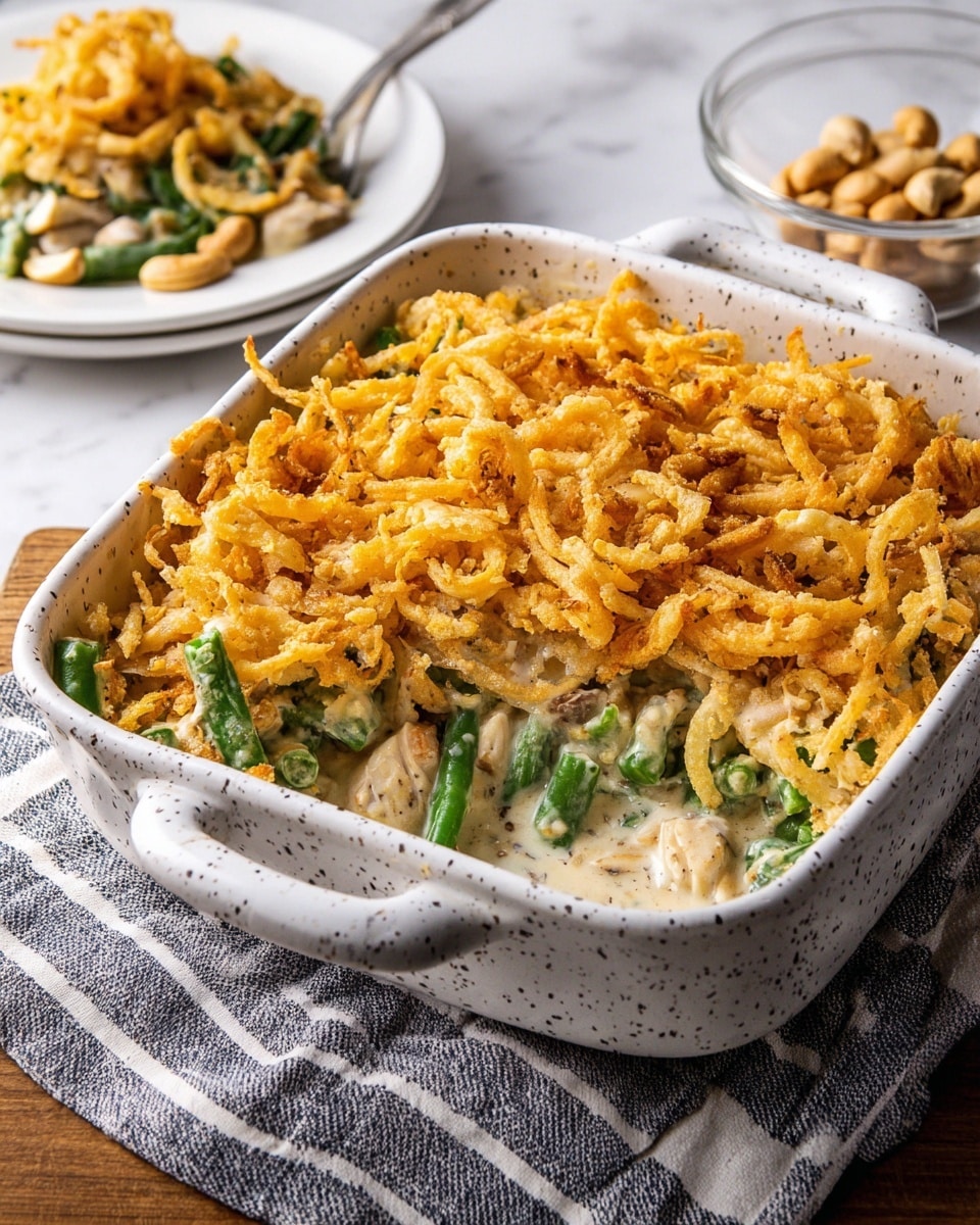 A white bowl filled with green beans mixed into a creamy white sauce, topped with light golden-brown crispy fried onions scattered all over. A wooden spoon is lifting a portion of green beans and fried onions, showing the bright green beans coated in the creamy sauce and crunchy topping. The bowl sits on a white marbled surface with a red-striped cloth partly visible. Photo taken with an iphone --ar 4:5 --v 7