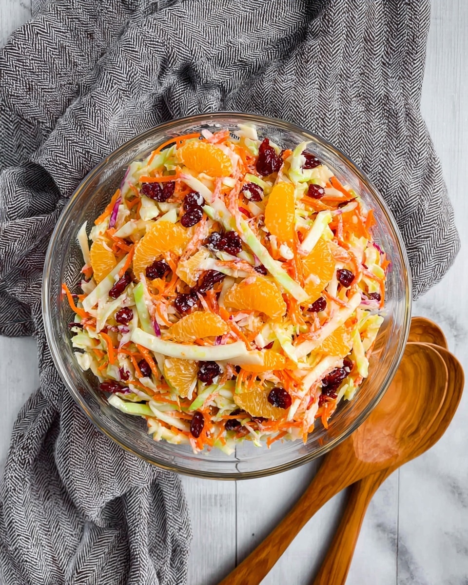 A close-up of a wooden spoon holding a colorful fruit and vegetable salad with multiple layers: thin orange carrot sticks, white apple slices with a slight red edge, bright orange segments, dark red dried cranberries, and pale green cucumber pieces. The mixture looks fresh and slightly creamy, indicating a light dressing. The background shows more of the same salad on a white marbled texture. photo taken with an iphone --ar 4:5 --v 7
