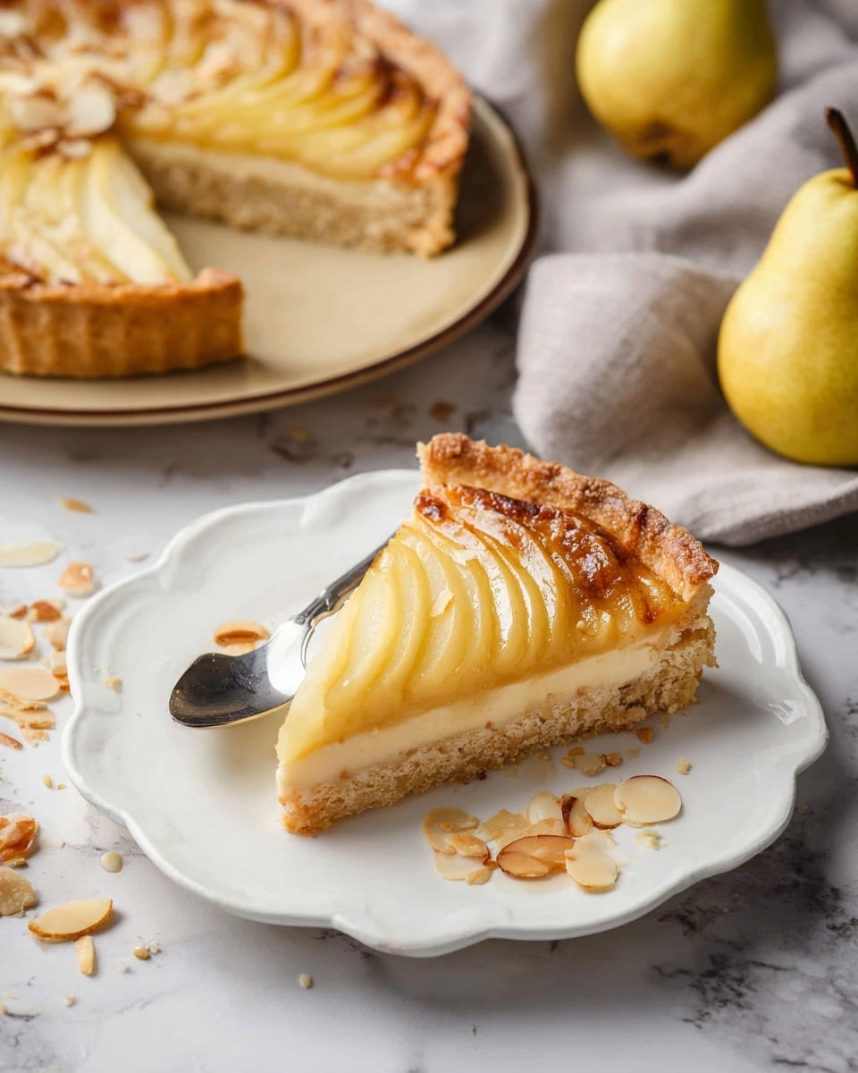 A single slice of pear tart sits on a white scalloped-edge plate, showing three distinct layers: a golden-brown crumbly crust at the base, a light beige almond filling in the middle, and thinly sliced, glossy yellow pears arranged in a fan shape on top. Some browned almond flakes are scattered around the edges and a few crumbs lie on the plate. Next to the slice, there is a silver spoon resting partially under it. The background shows the rest of the tart on a beige plate, two whole pears, and a light grey cloth on a white marbled surface. photo taken with an iphone --ar 4:5 --v 7