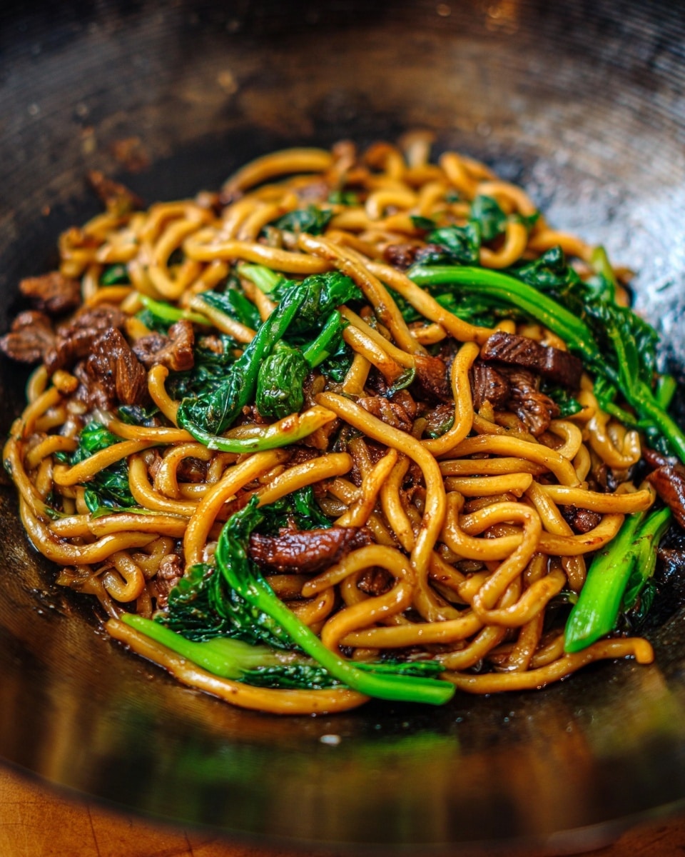 A white bowl is filled with three main layers: shiny orange-brown cooked noodles forming the largest base layer, mixed with dark brown, glistening pieces of cooked meat scattered throughout, and bright green leafy vegetables layered on top and mixed within. The noodles look thick and slightly twisted, while the dark meat pieces have a glazed texture. The green vegetables provide a fresh contrast with smooth and slightly shiny leaves. The bowl sits on a surface with a white marbled texture. Photo taken with an iphone --ar 4:5 --v 7