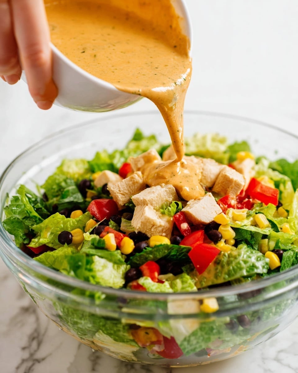 A close-up of a bowl filled with a smooth, creamy light orange sauce topped with small red chili flakes scattered on the surface. The bowl is white with a slight brown rim and sits on a white marbled texture. Around the bowl, there are a few lime slices and a lime wedge, along with a white spoon that has a light brown handle resting next to the bowl. Photo taken with an iphone --ar 4:5 --v 7